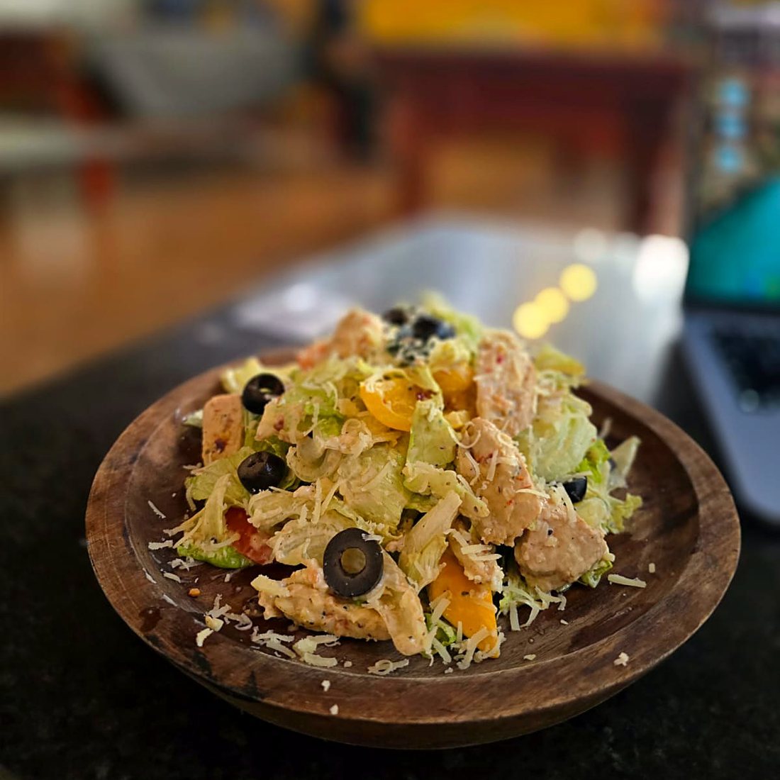 Caesar salad with chicken and parmesan in a wooden bowl